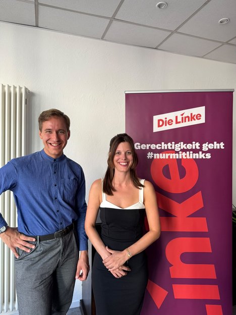 Ein Bild, das zwei Personen vor einer Wand zeigen